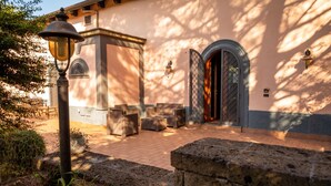 An outdoor seating area with wicker furniture, a stone wall, and a lamp post. - Villetta Capodimonte Guest House (Naples)