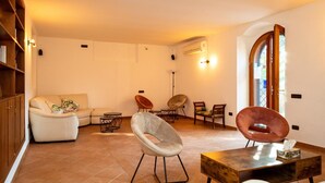 A living room with a sofa, chairs, a coffee table, and a bookshelf. - Villetta Capodimonte Guest House (Naples)