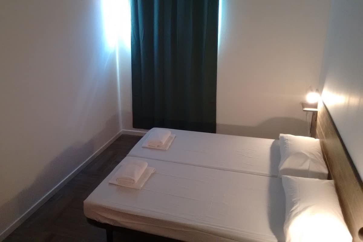 Ein Hotelzimmer mit zwei Betten, einem Spiegel und einem fenster mit Vorhängen.