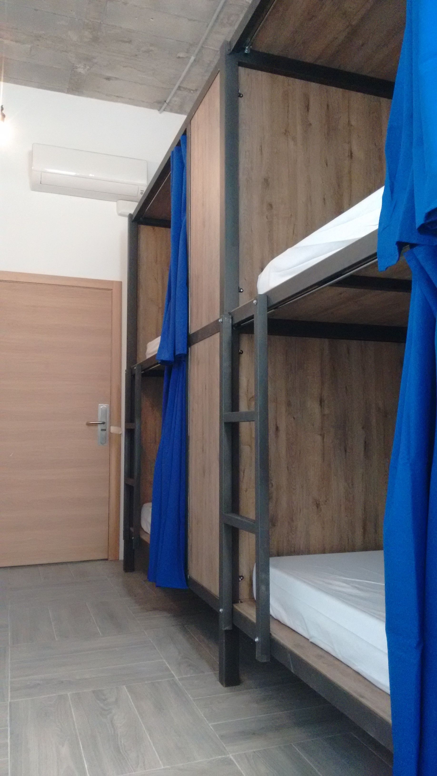 Un dormitorio con literas, una puerta de madera y suelo de baldosas.