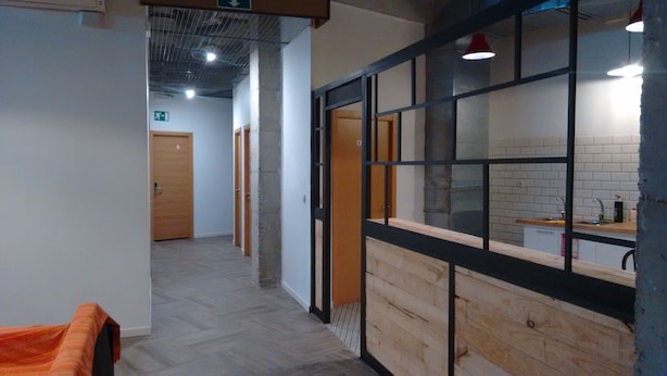 Un couloir au plancher de bois, un coin cuisine avec un mur de fond en briques et une porte portant le numéro 4.