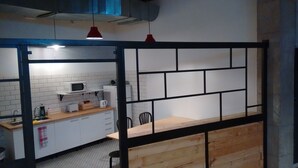 Une cuisine avec des meubles blancs, un four à micro-ondes, une bouilloire et un plan de travail en bois.