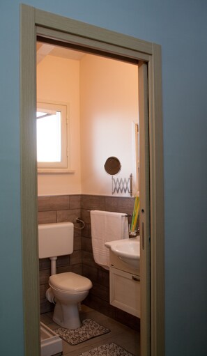 A small bathroom with a toilet, sink, and a window.