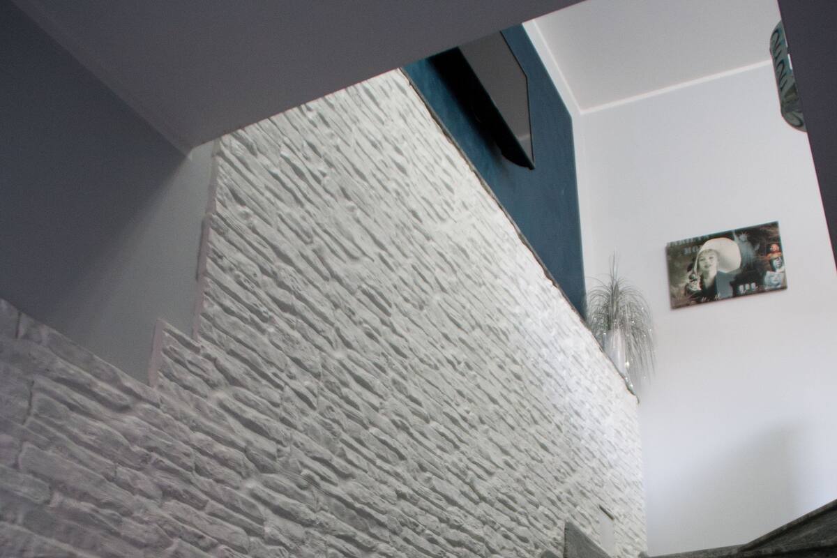 Un escalier avec un mur en pierre d’un côté et un escalier en bois sombre de l’autre.