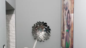 A hallway with a decorative metal flower on the wall, a framed picture, and a stone accent wall. - The Liberty Palace b&b (Campobello di Licata)