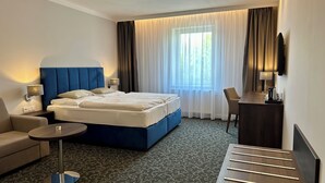 A hotel room with a large bed, a desk, a chair, and a TV. - Penzion Village (Karlovy Vary)