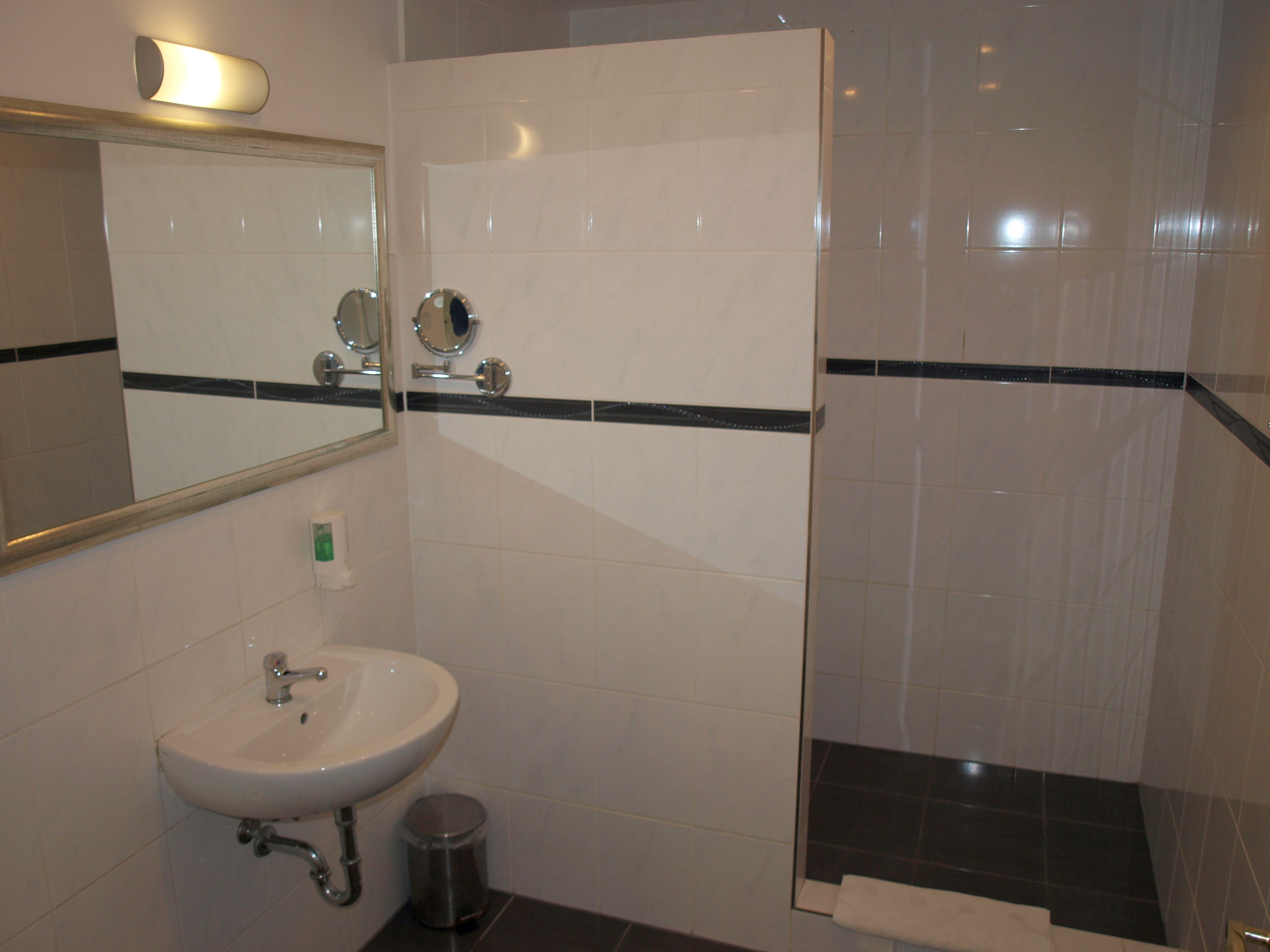 A bathroom with a sink, mirror, and shower area.