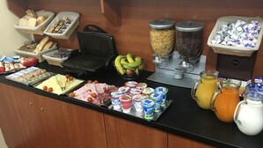 A breakfast buffet with various food items, including bread, pastries, fruits, and beverages. - Penzion Village (Karlovy Vary)