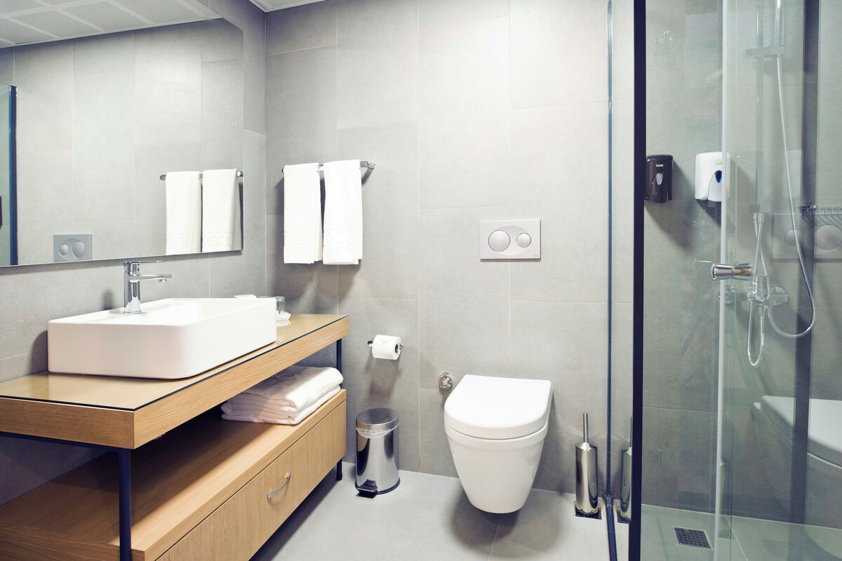 Un baño moderno con cabina de ducha de vidrio, un lavamanos blanco y un inodoro.