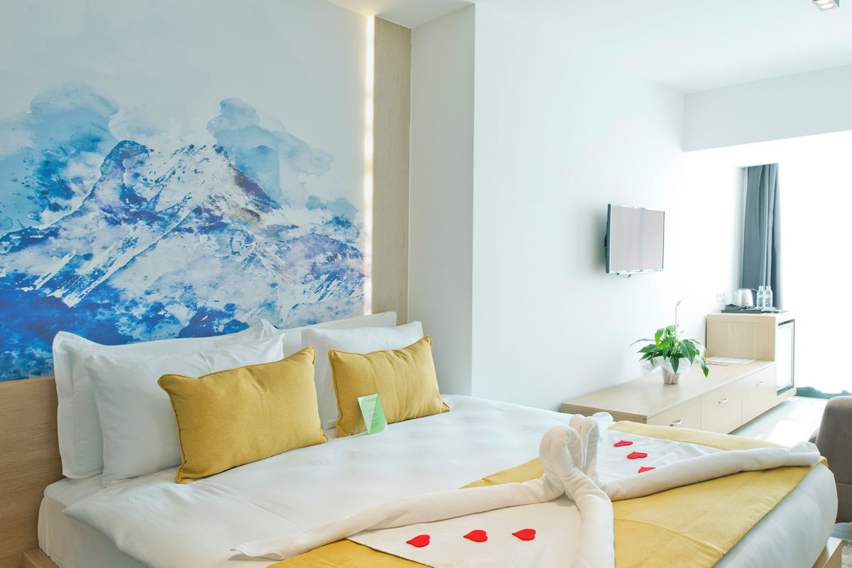 Habitación de hotel con una cama grande, un sofá, un escritorio y una televisión.