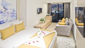 A hotel room with a bed, a sofa, a TV, and a window with a city view. - Hotel 86 by Katipoglu (Izmir)