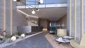 Un hall d’hôtel moderne comprenant un comptoir d’accueil, un espace salon et un escalier menant aux étages supérieurs.
