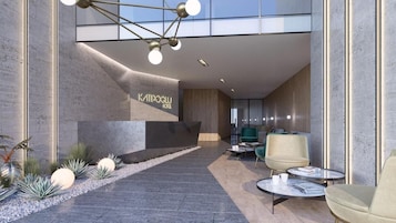 A modern hotel lobby with a reception desk, seating area, and a staircase leading to upper floors.