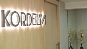 Une porte en bois sur laquelle le nom « KORDELY » est inscrit en grandes lettres et illuminé.