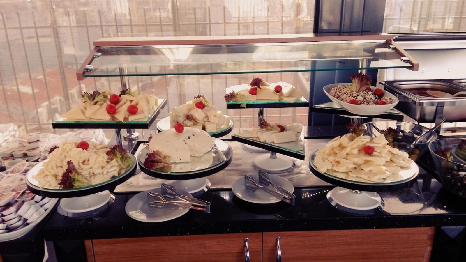 A buffet with various dishes, including salads, fruits, and desserts, displayed on glass shelves.
