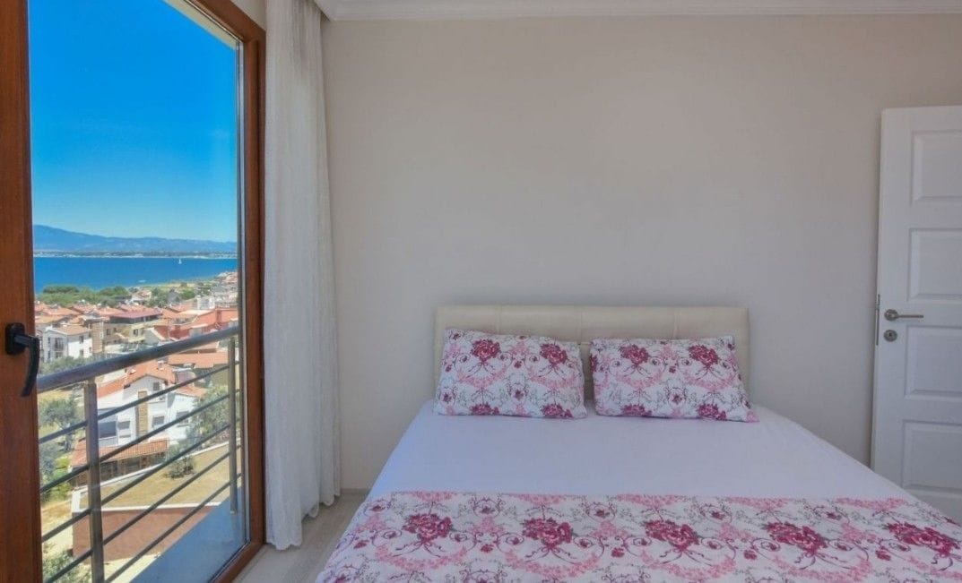 Een slaapkamer met een bed, bloemenbeddengoed, uitzicht op zee en een balkon.