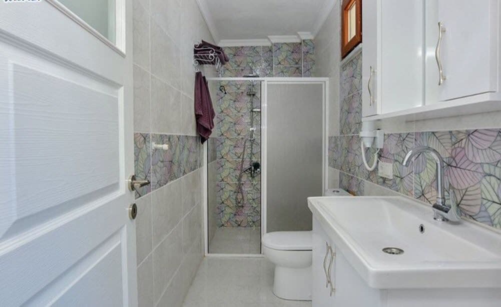 Een kleine badkamer met douche, toilet en wastafel.