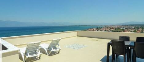 A terrace with a view of the sea and a distant cityscape.