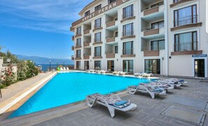 A hotel with a swimming pool, lounge chairs, and a reception area.