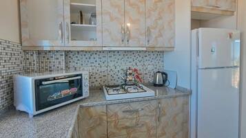 A kitchen with a microwave, gas stove, and a refrigerator.
