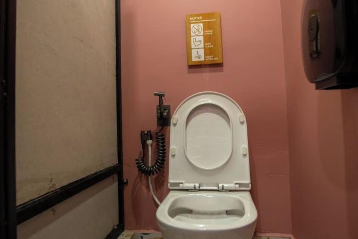 A bathroom with a toilet, a hand dryer, and a notice board with safety instructions.