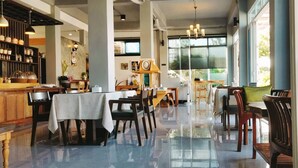 A spacious restaurant with high ceilings, large windows, and a variety of seating arrangements including tables and chairs. - Koh Larn Riviera (Koh Lan)