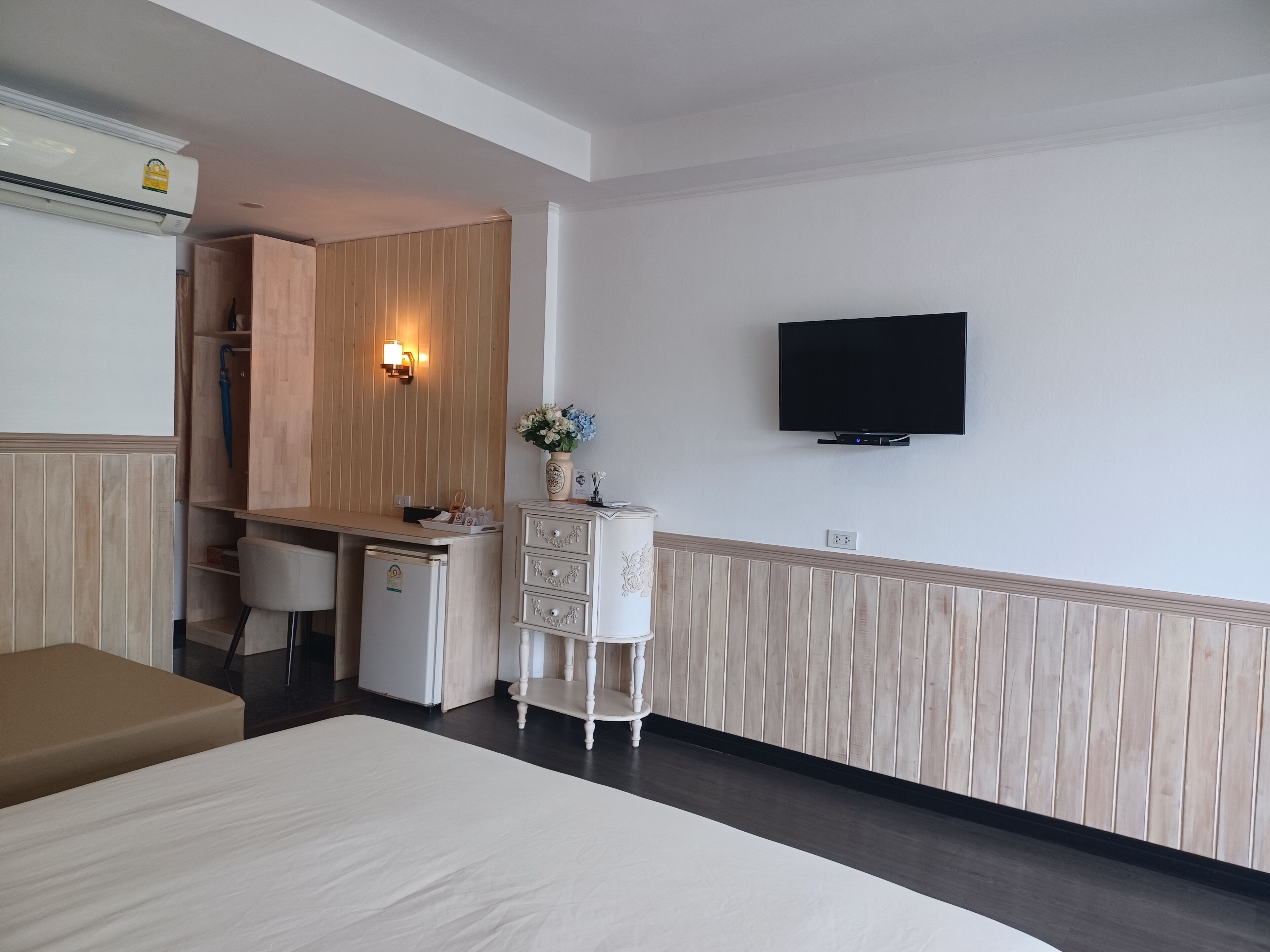 Una habitación de hotel con cama, escritorio, televisor y minibar.
