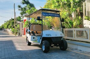 A golf cart parked on a paved street with a sign reading "Kohl Larn RIVIERA".