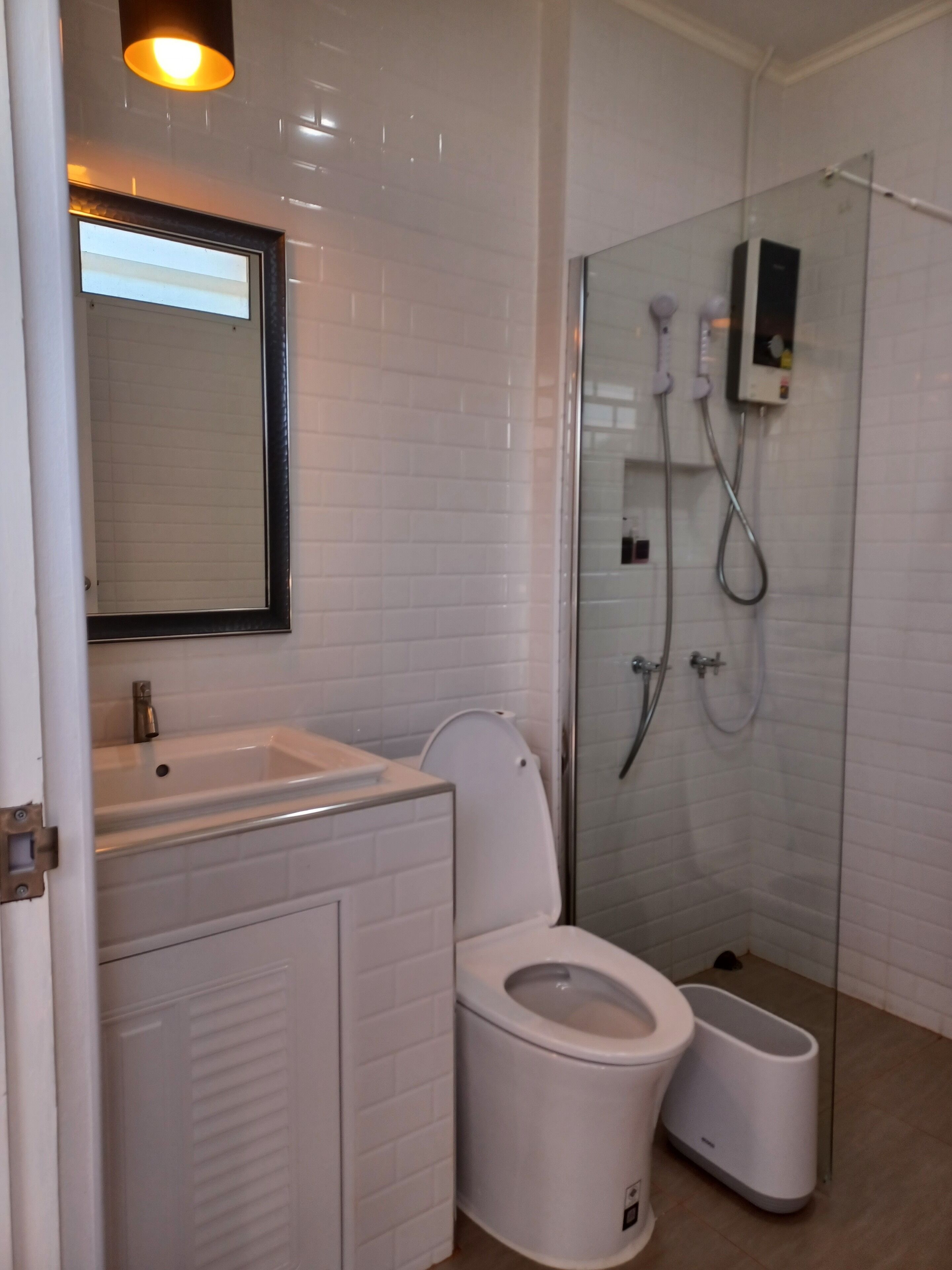 A modern bathroom with a white sink, toilet, and glass shower enclosure.