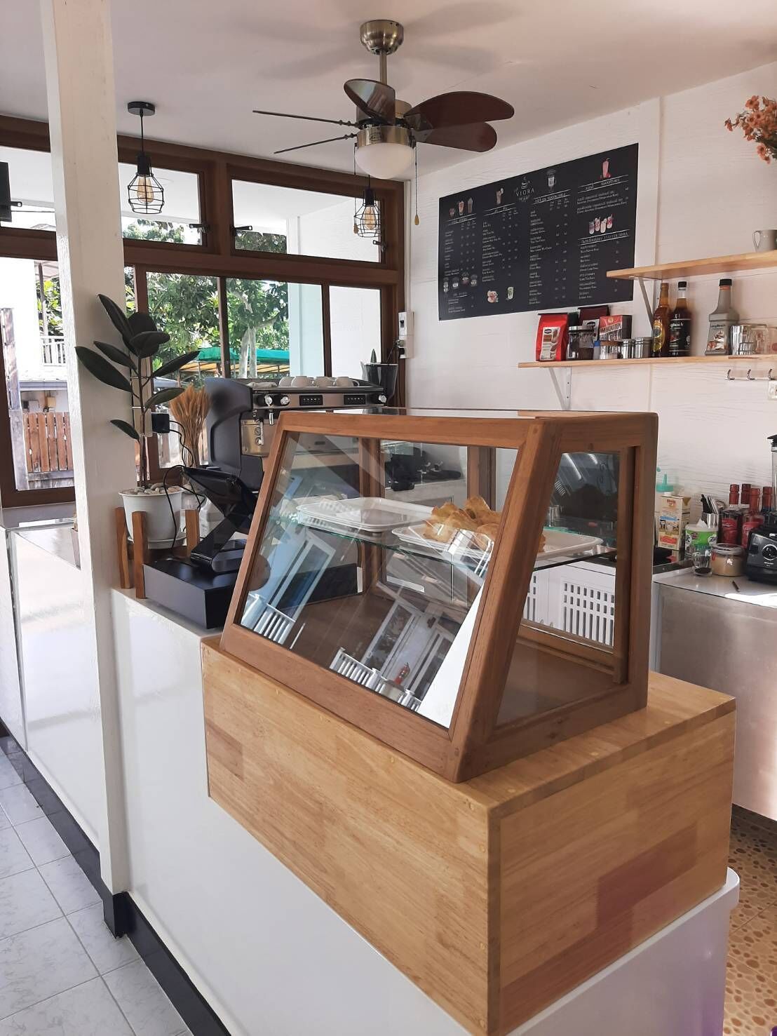 Een café met een houten toonbank, een menubord en een plafondventilator.