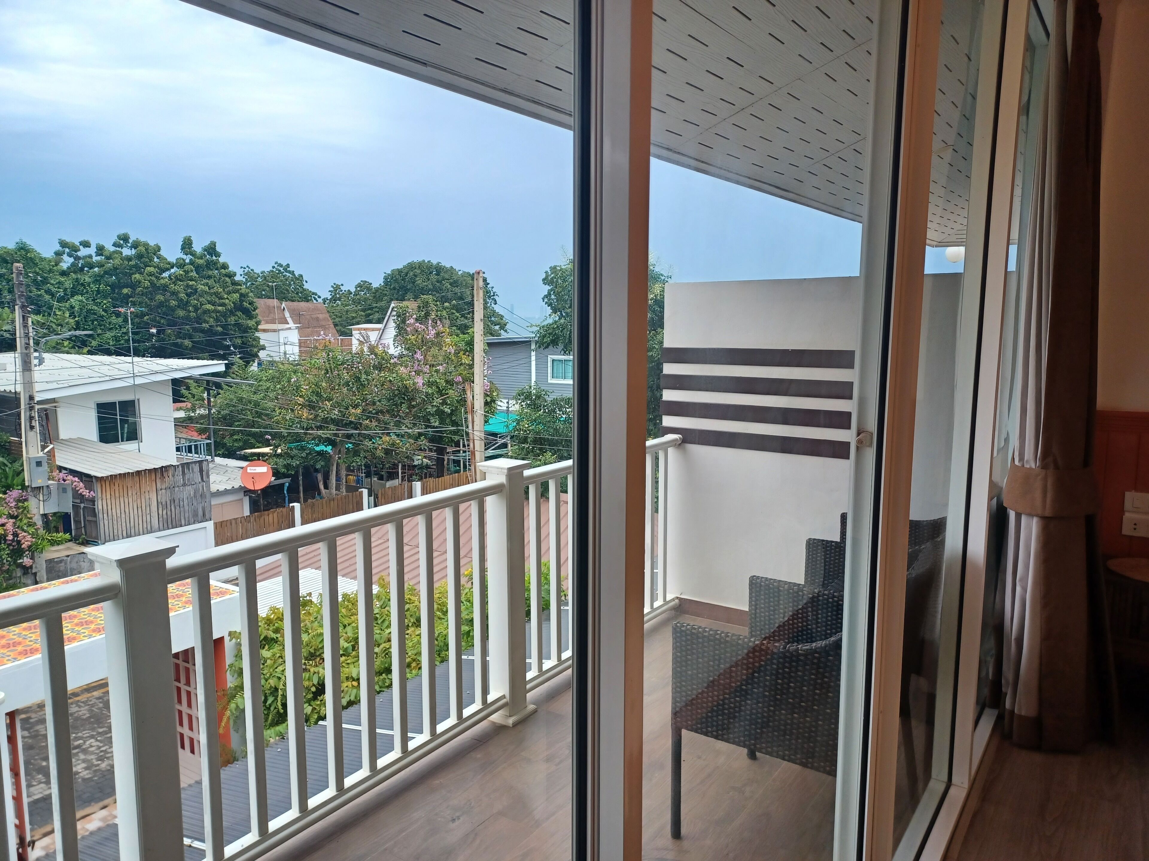 A balcony with a view of neighboring houses and greenery.