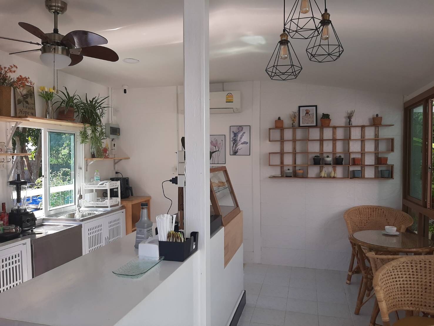 A modern kitchen with a central island, wooden shelves, and a dining area with wicker chairs.