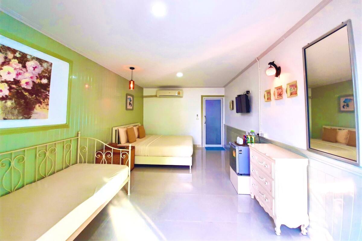 A hotel room with a bed, a dresser, a mirror, and a painting on the wall.