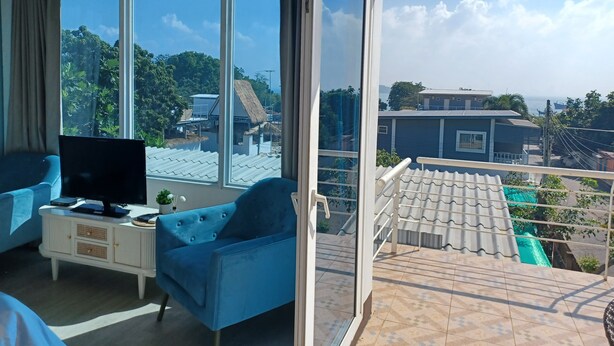 A modern living room with a large sliding glass door leading to a balcony. - Koh Larn Riviera (Koh Lan)
