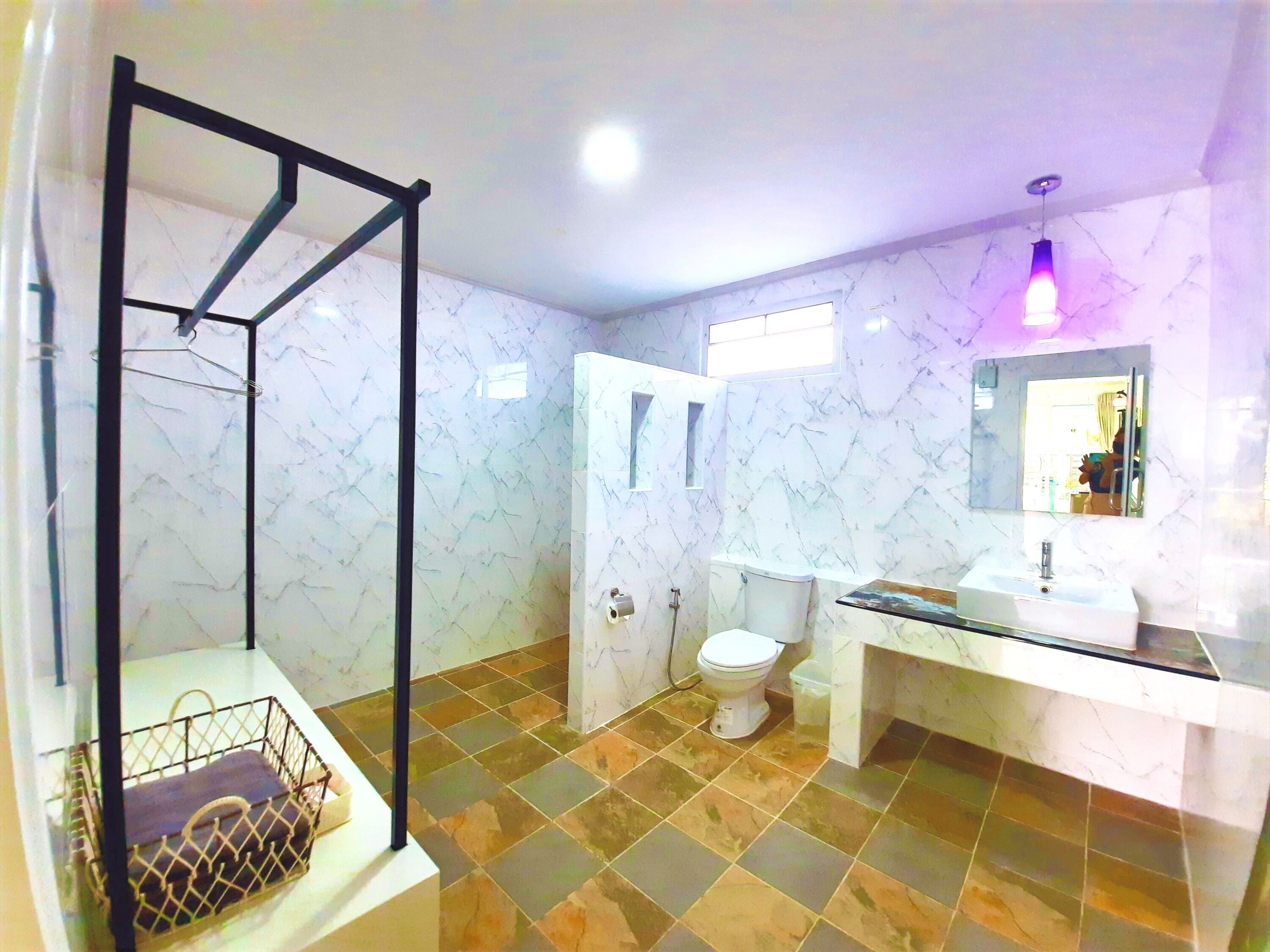 A bathroom with a marble wall, a glass shower enclosure, a sink, and a toilet.