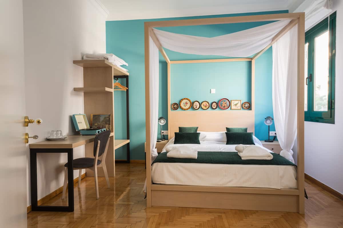 A four-poster bed with a canopy, a desk with a chair, and a shelf with decorative items.