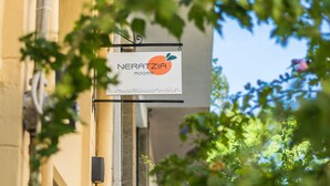 A building with a sign for 'NERATZIA Rooms' and a row of parked cars in the background. - Neratzia Rooms (Athens)