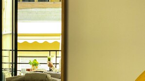 A hotel room with a bed, a window with a view of the street, and a balcony with a railing. - Neratzia Rooms (Athens)