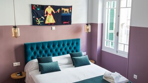 A bedroom with a large bed, a wooden floor, a window with shutters, and a wall painting. - Neratzia Rooms (Athens)