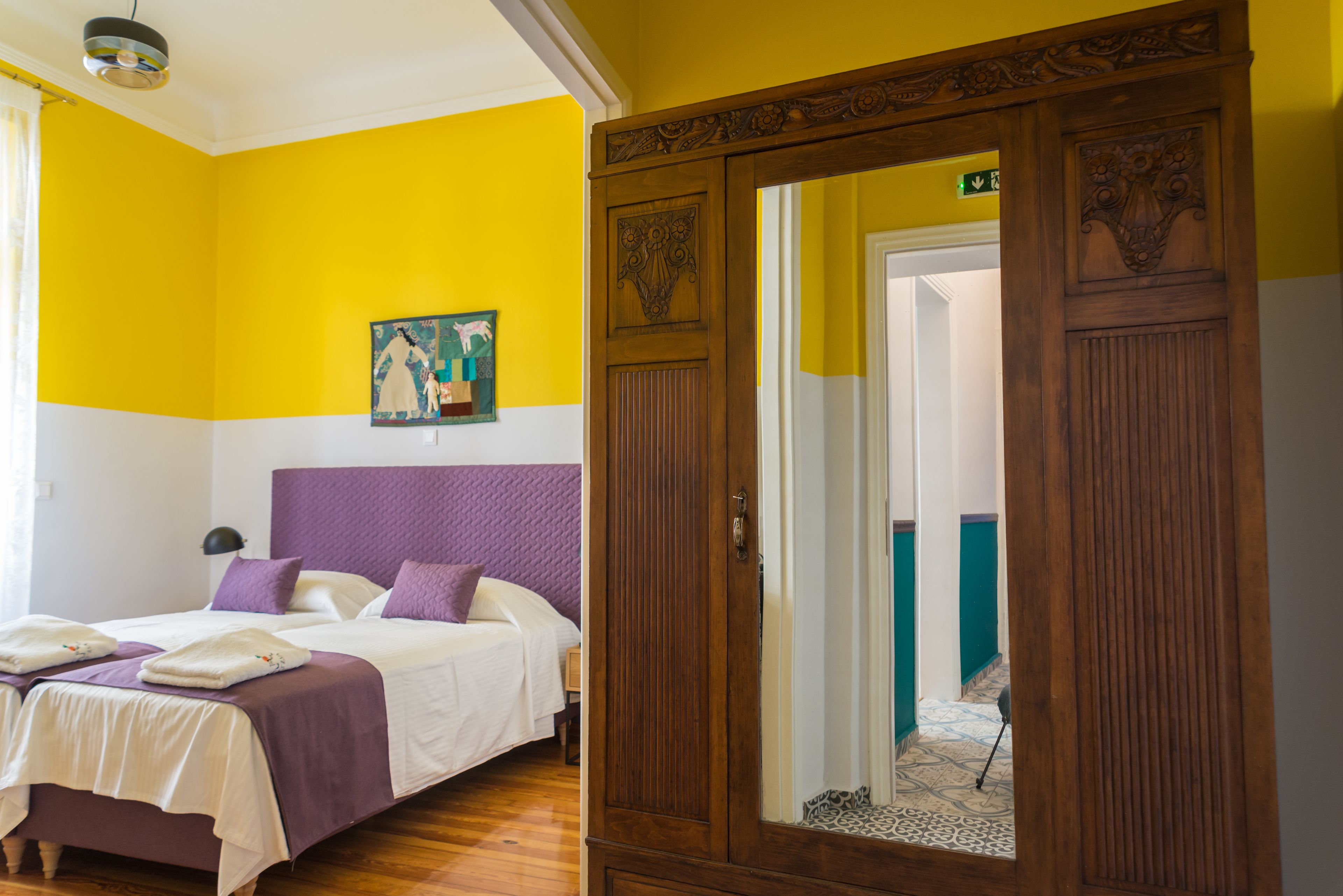 A room with a bed, a wooden wardrobe, and a painting on the wall.