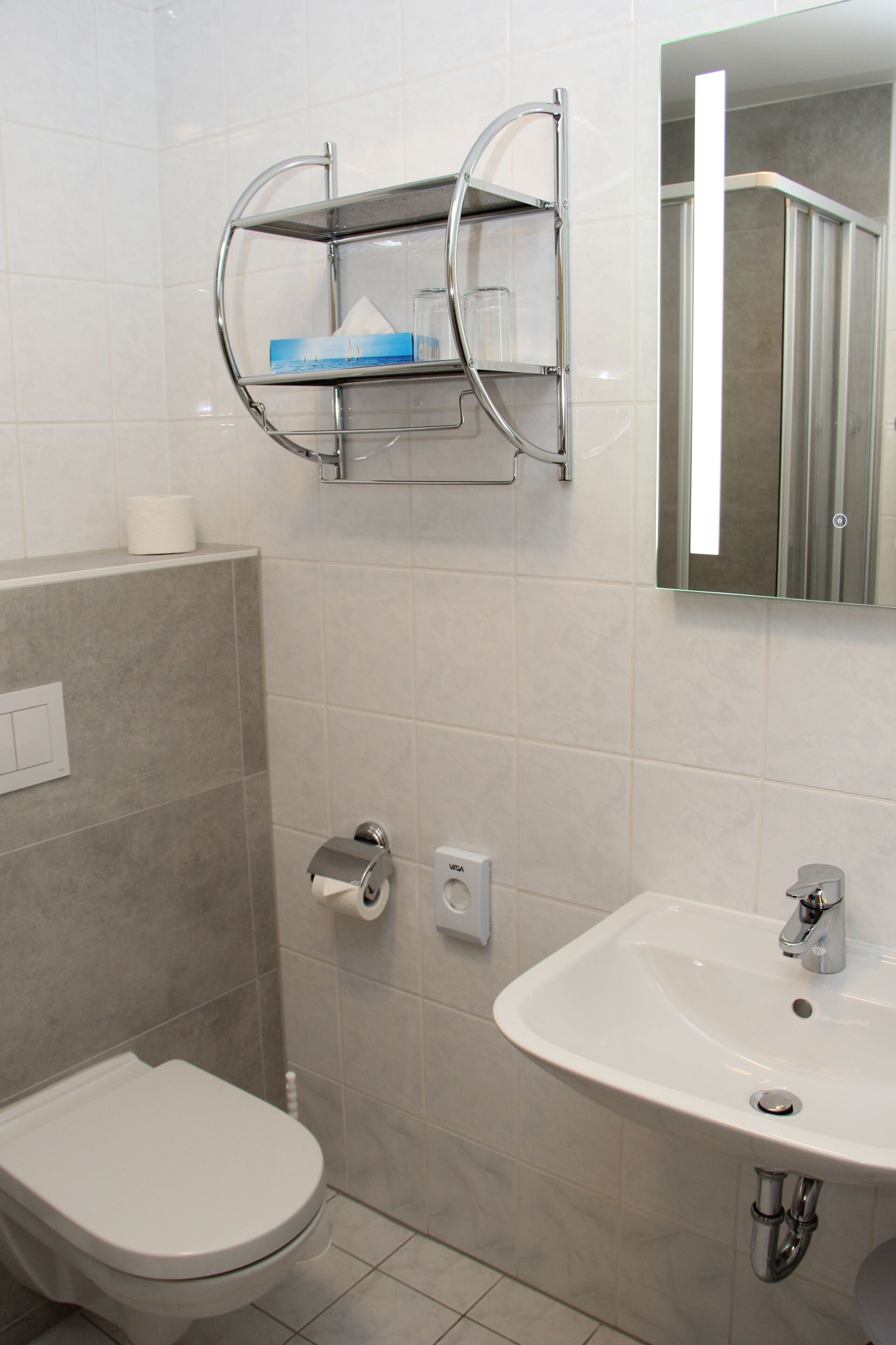 A bathroom with a toilet, a sink, and a mirror.
