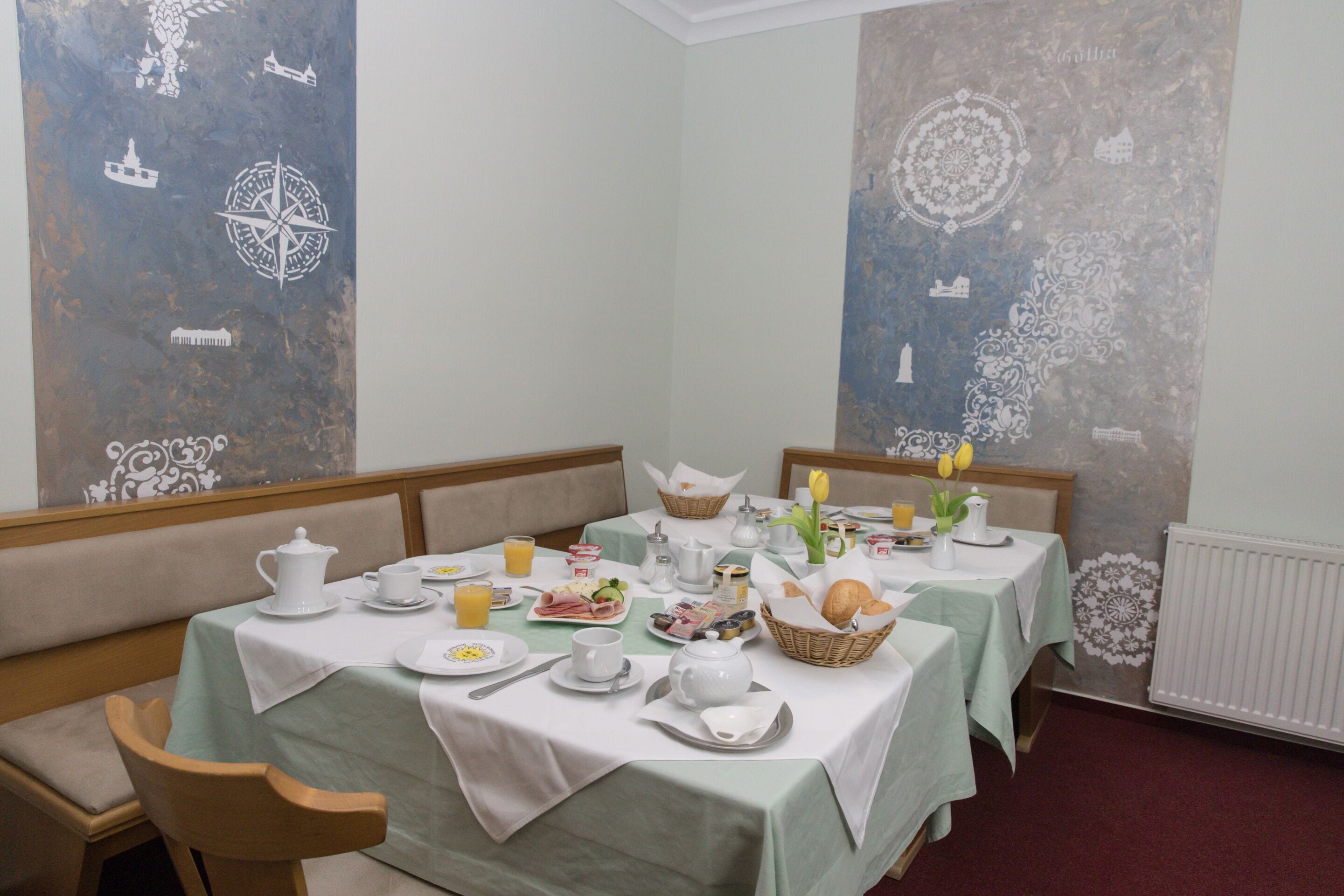 A dining area with two tables set for breakfast, featuring plates, cups, and a variety of breakfast items.