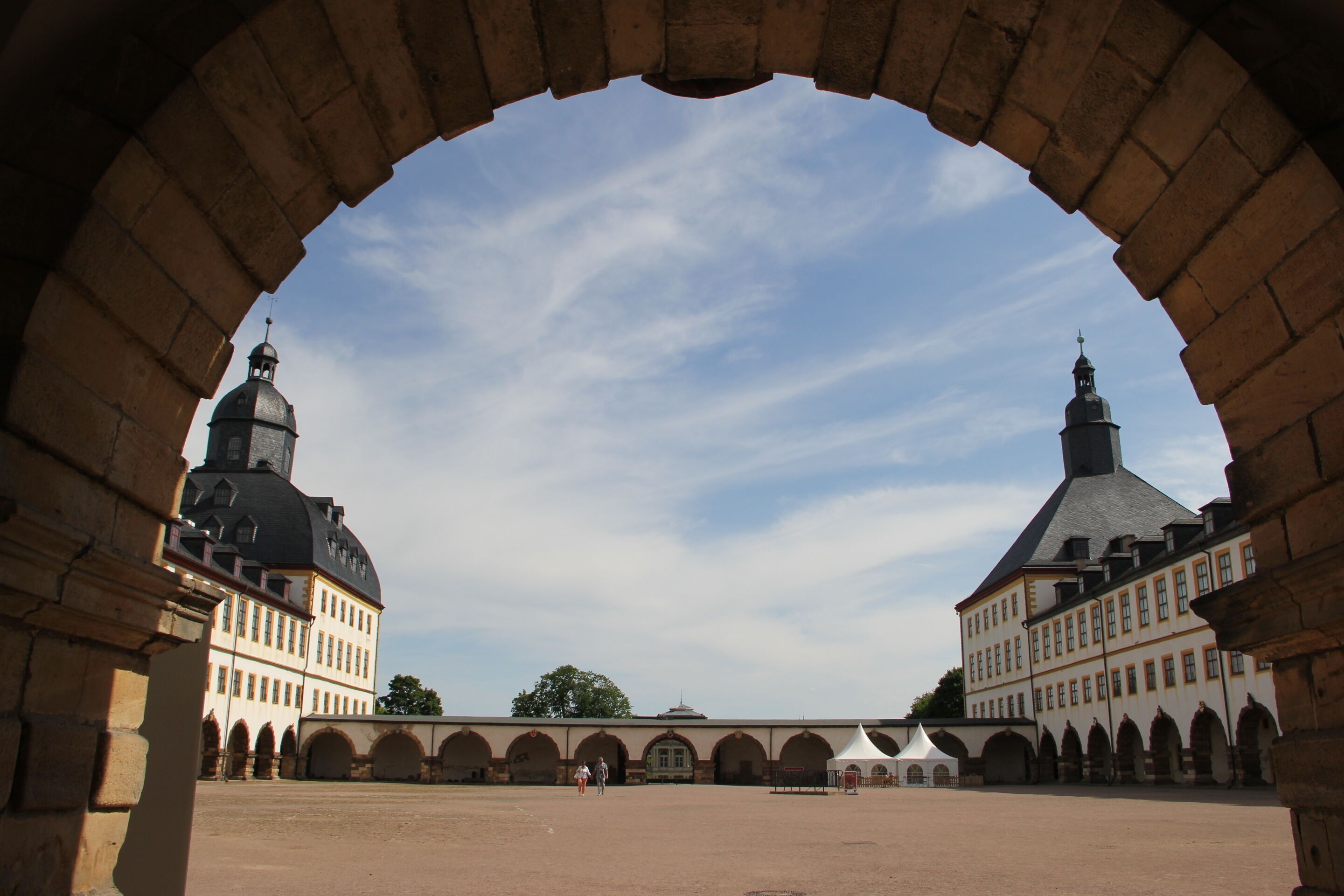 Ein Innenhof mit einem großen Bogen, der ein Gebäude mit zwei Kuppeltürmen rahmt.