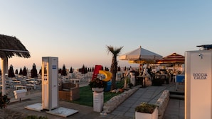 Un resort frente a la playa con sillones de sol, una zona de juegos y comedor al aire libre.