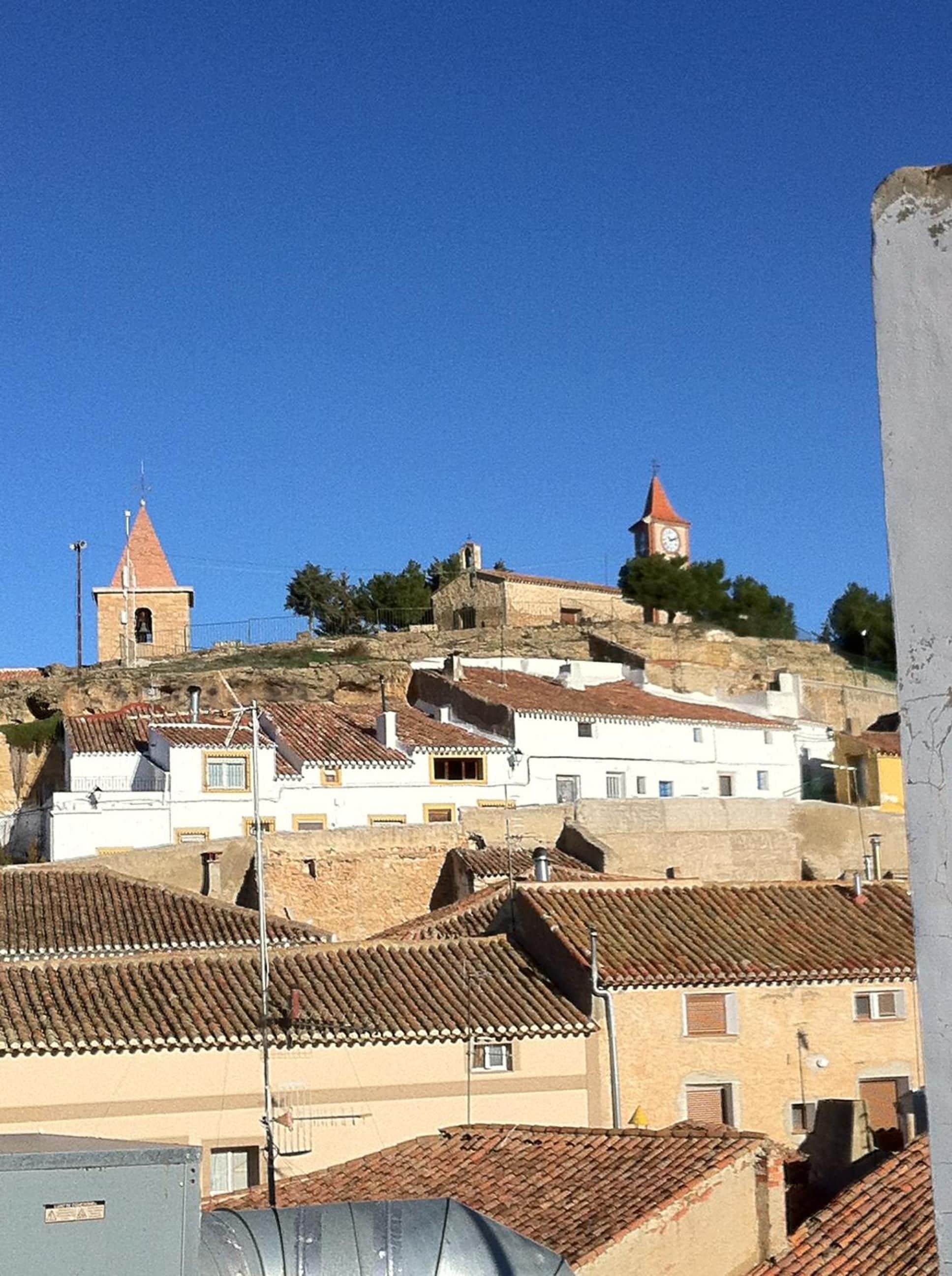A town with buildings on a hill, including a church with a bell tower and a clock tower.