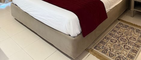 A hotel room with a large bed, a wardrobe, a nightstand, a lamp, and a framed picture on the wall.