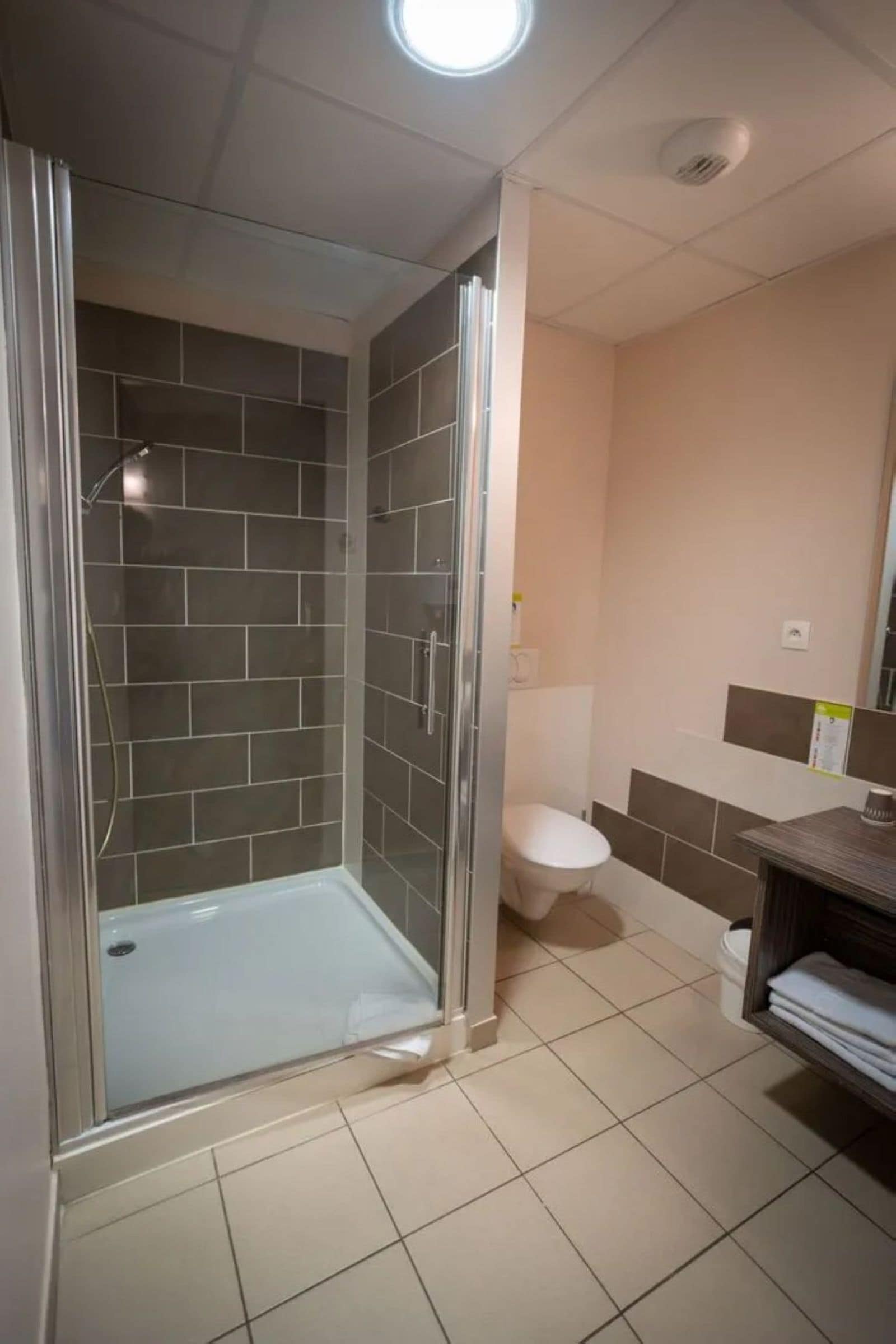 A bathroom with a glass-enclosed shower, a toilet, and a sink area.