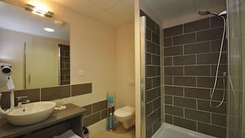 Een moderne badkamer met een wastafel, spiegel, toilet en douche.