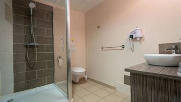 A modern bathroom with a glass-enclosed shower, a white toilet, and a wooden vanity with a sink.