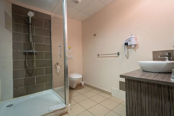 A modern bathroom with a glass-enclosed shower, a white toilet, and a wooden vanity with a sink.